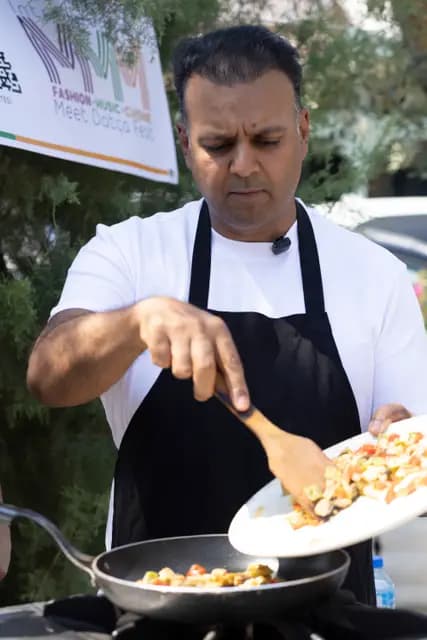 Şef doğranmış sebzeleri tabaktan tavaya kaydırırken gastronomi anı tam kıvamında yakalanıyor.