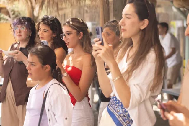Genç bir izleyici grubu telefonlarını kaldırmış atölyeyi kayda alıyor.