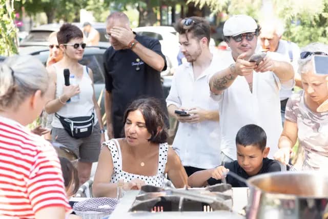 Mutfak gösterisini çevreleyen kalabalık telefonlarıyla kaydediyor; ön sırada çocuklar var.