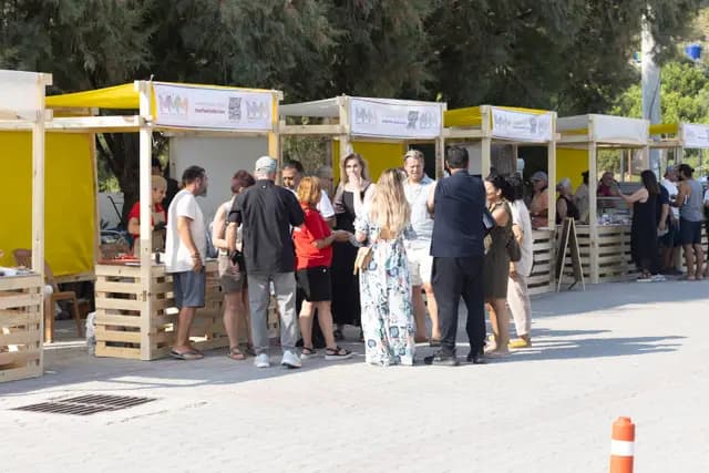 Palamutbükü'nde sıralanan sarı festival stantları ve aralarında dolaşan ziyaretçiler.