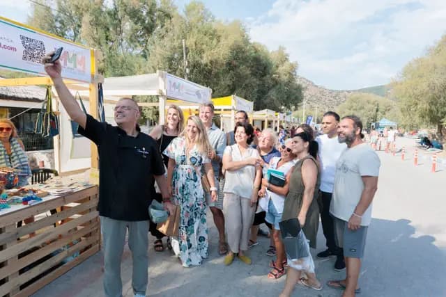 Festival alanında toplu hatıra karesi; öndeki katılımcı telefonuyla kalabalığı çekiyor.