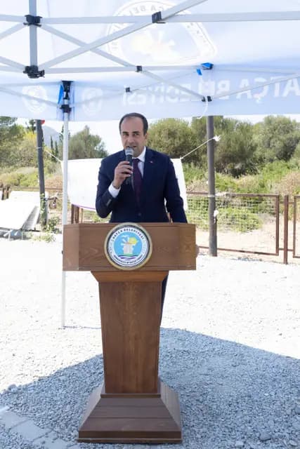 Kürsüde takım elbiseli konuşmacı mikrofonla kadın kooperatiflerine dair sunumunu yapıyor.